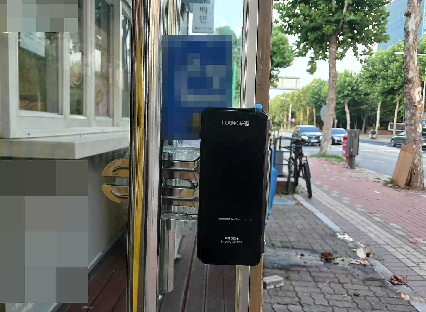 동대문구 신설동 출장 — 거리에 면한 상가 유리문에 달린 검은 도어락 본체와 금빛 받침, 스테인리스 세로 손잡이